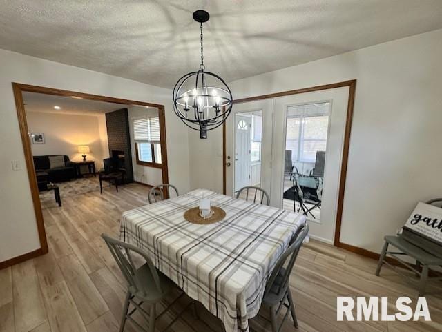 dining room featuring light wood-type flooring, baseboards, and a notable chandelier