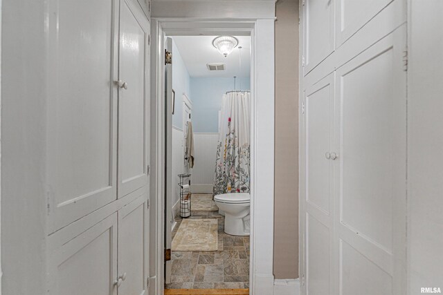 bathroom with visible vents, toilet, stone finish flooring, and a shower with shower curtain