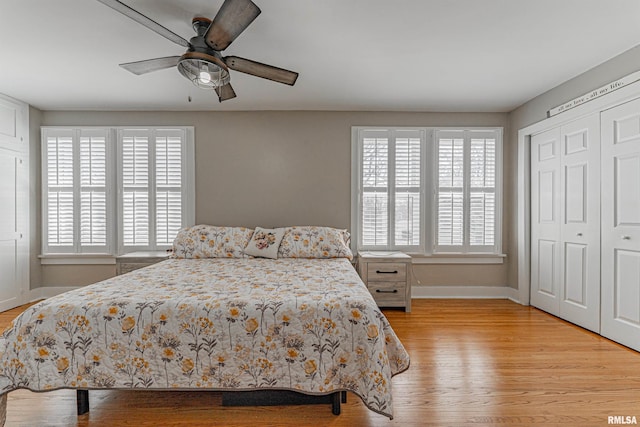 bedroom with a closet, baseboards, light wood-style floors, and a ceiling fan