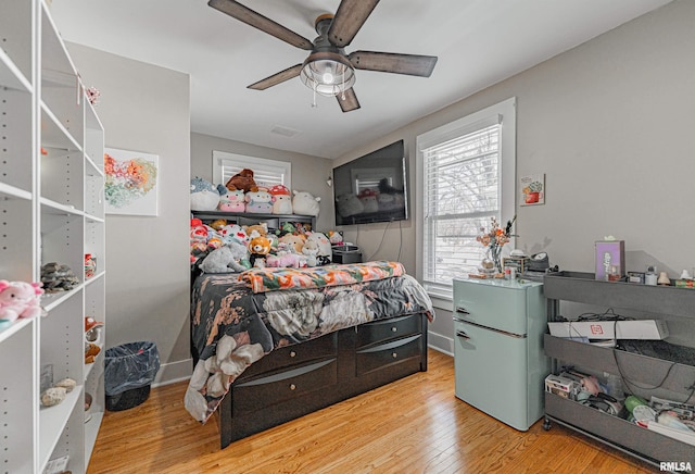 bedroom featuring ceiling fan, visible vents, wood finished floors, and freestanding refrigerator