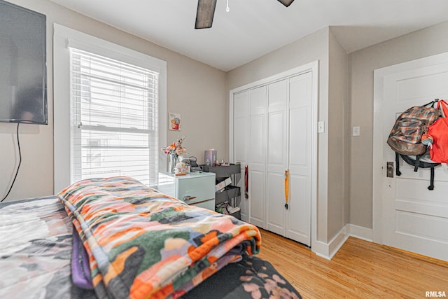 bedroom with baseboards, light wood-style floors, a closet, and ceiling fan