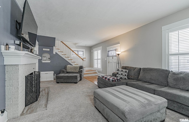 living area featuring a brick fireplace and stairs