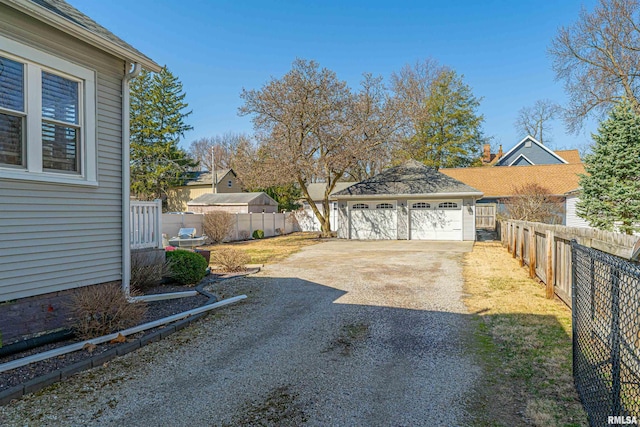 view of yard with a fenced backyard, a detached garage, and an outdoor structure