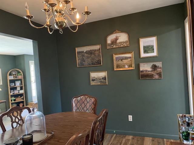 dining space with baseboards, wood finished floors, and a chandelier