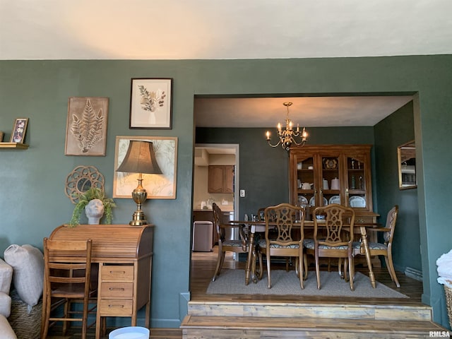 dining space featuring wood finished floors, baseboards, and a chandelier