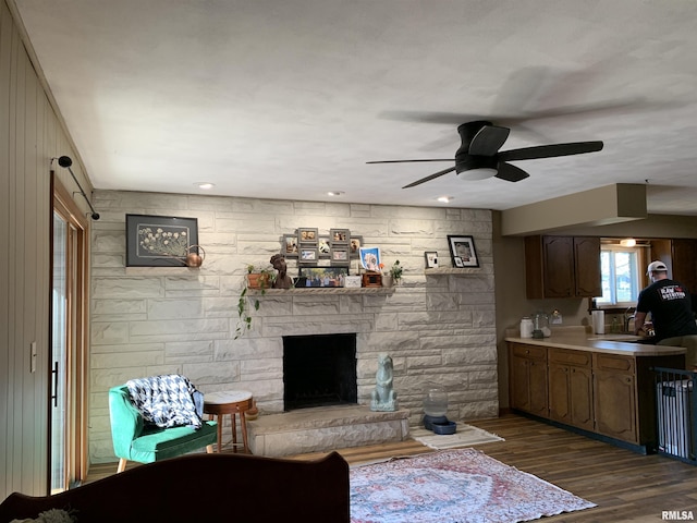 living room with a fireplace, dark wood-type flooring, and a ceiling fan