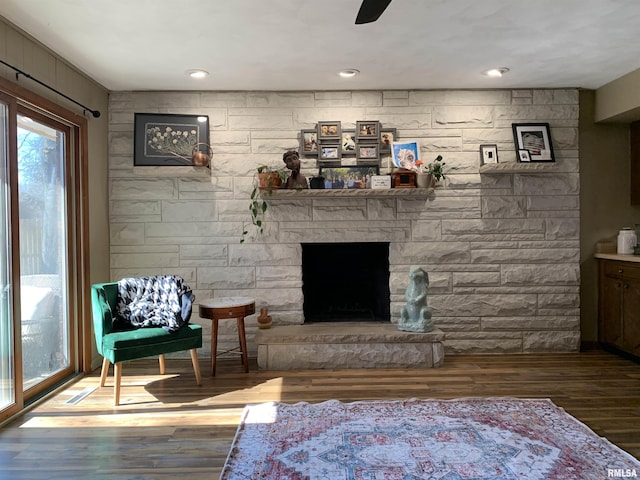 living area with a fireplace, a ceiling fan, and wood finished floors