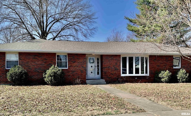 ranch-style house featuring a front yard, brick siding, and a shingled roof