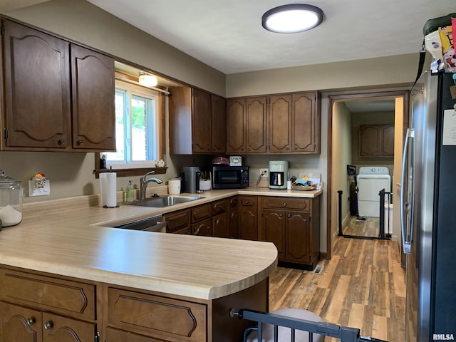 kitchen featuring a sink, washer and clothes dryer, light countertops, and stainless steel appliances