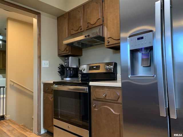 kitchen featuring light countertops, wood finished floors, under cabinet range hood, and stainless steel appliances