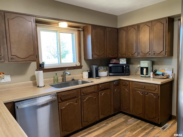 kitchen featuring visible vents, light wood finished floors, a sink, stainless steel appliances, and light countertops