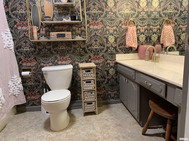 bathroom with baseboards, toilet, vanity, and wallpapered walls