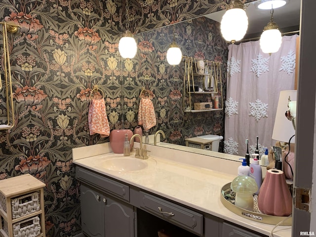 full bath with toilet, wallpapered walls, and vanity