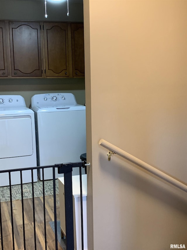 laundry area with cabinet space, wood finished floors, and washer and clothes dryer