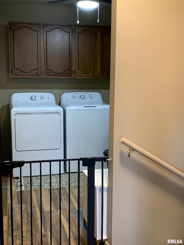 clothes washing area featuring wood finished floors, cabinet space, and washing machine and dryer