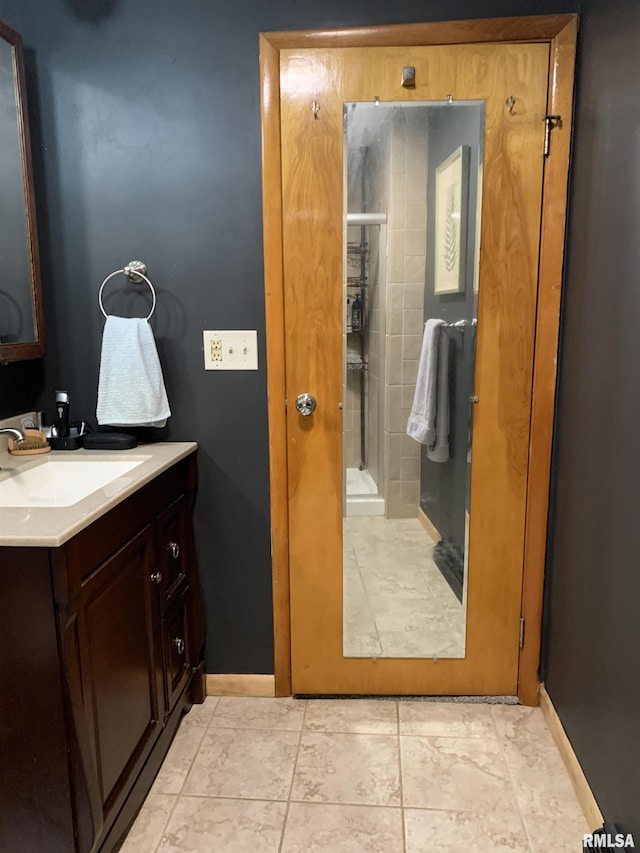 full bath featuring a shower stall, vanity, and baseboards