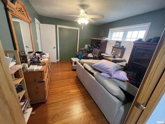 bedroom featuring light wood finished floors, a textured ceiling, and ceiling fan