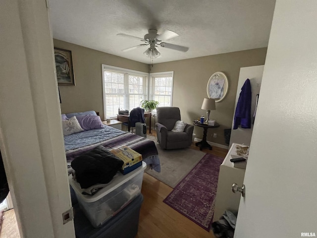 bedroom with baseboards, a textured ceiling, ceiling fan, and wood finished floors