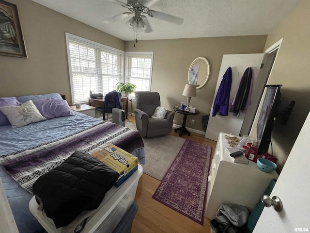 bedroom with a ceiling fan, wood finished floors, and baseboards