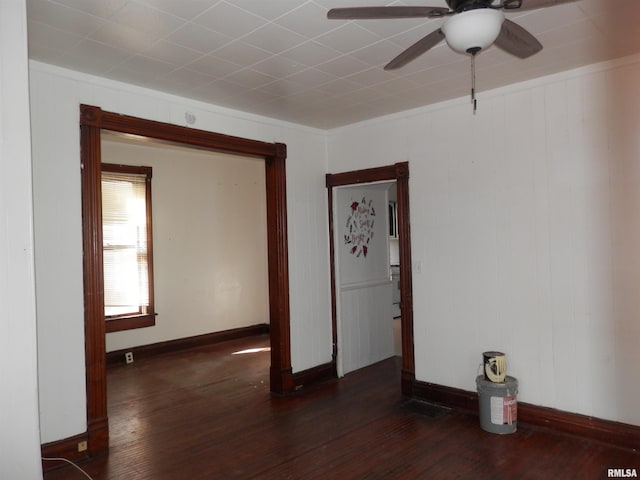 empty room featuring dark wood finished floors, a ceiling fan, and baseboards