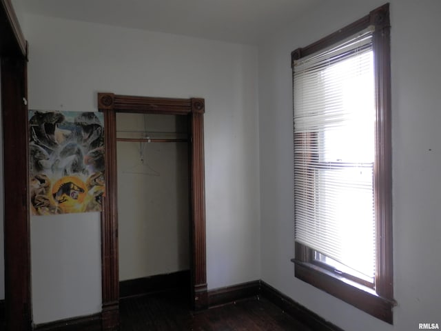 unfurnished bedroom with dark wood finished floors, multiple windows, and baseboards