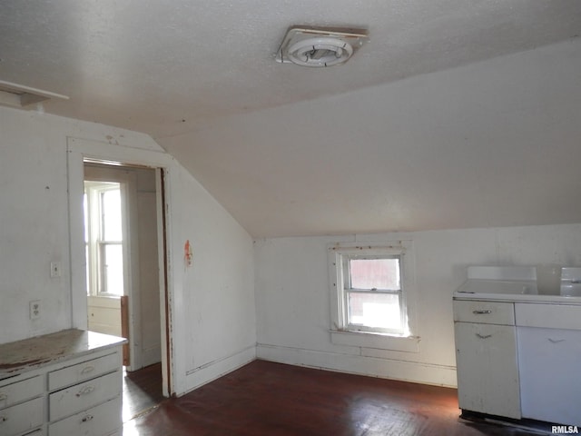 bonus room featuring plenty of natural light, a textured ceiling, dark wood-style floors, and vaulted ceiling