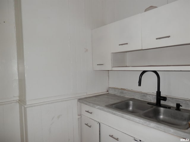 kitchen featuring white cabinets, light countertops, and a sink