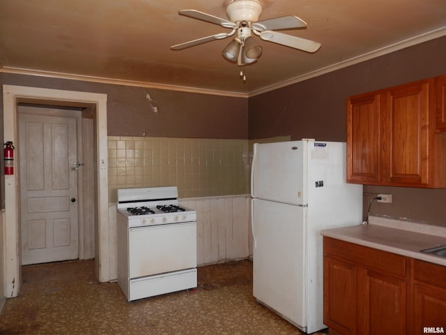 kitchen with tile patterned floors, ornamental molding, brown cabinetry, white appliances, and a ceiling fan