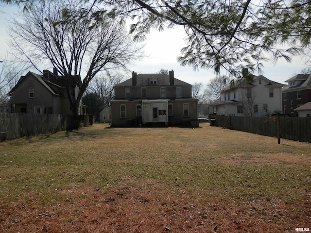 rear view of house featuring a yard and fence