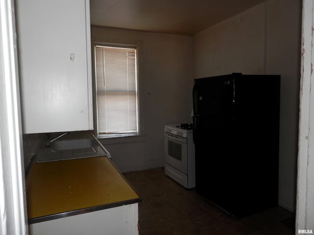 kitchen featuring freestanding refrigerator, gas range gas stove, and a sink