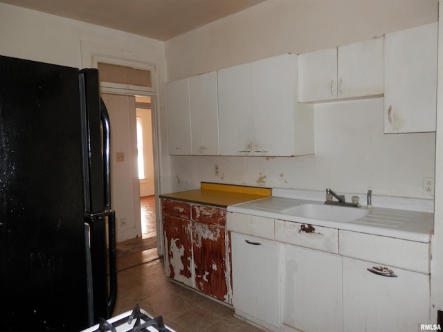 kitchen with white cabinetry, freestanding refrigerator, light countertops, and a sink