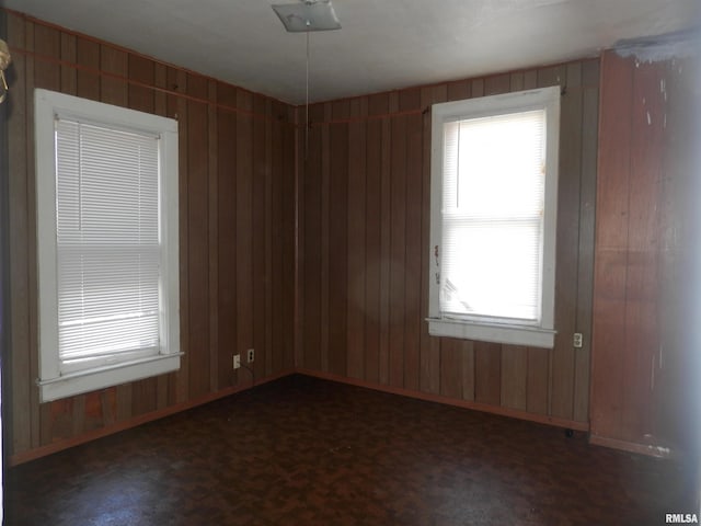 unfurnished room featuring wooden walls