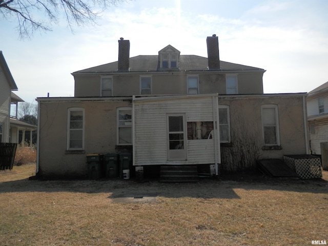 rear view of property with entry steps, a chimney, and a yard