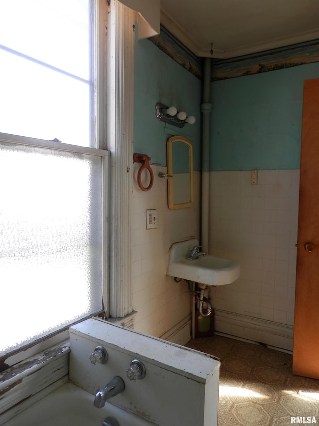 bathroom featuring a sink, tile walls, and wainscoting