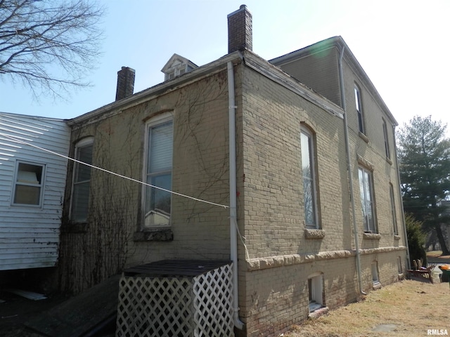 view of side of home featuring brick siding and a chimney