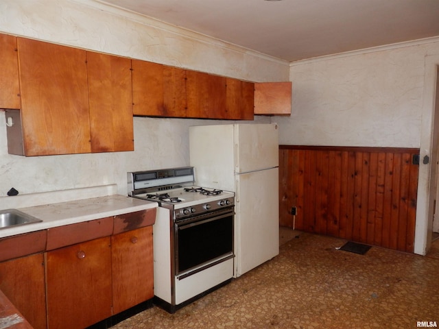 kitchen featuring white appliances, wooden walls, wainscoting, crown molding, and dark floors