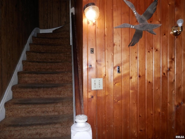 staircase featuring wooden walls