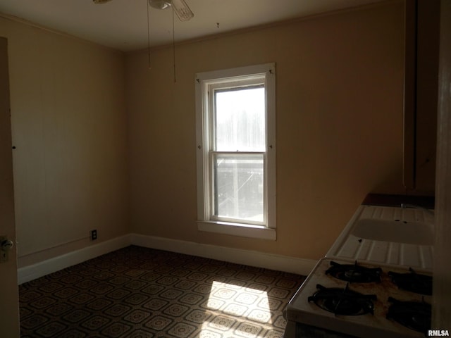 empty room with a sink, a ceiling fan, baseboards, and ornamental molding