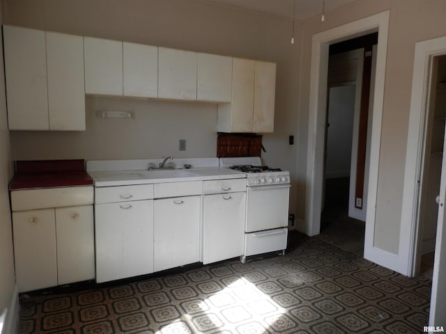 kitchen featuring white range with gas cooktop, white cabinetry, light countertops, and a sink