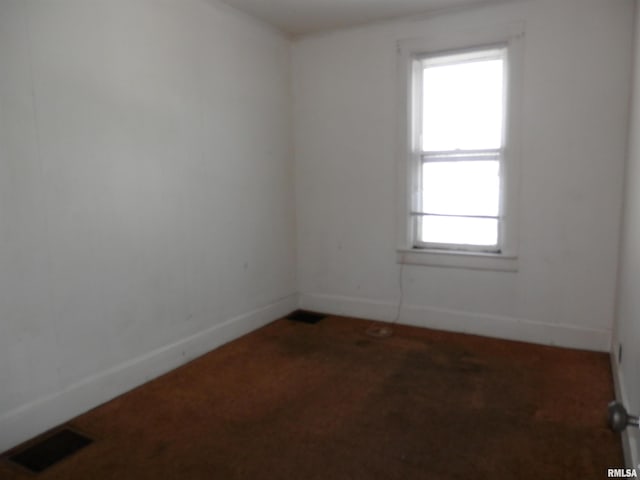 spare room with carpet flooring, baseboards, and visible vents