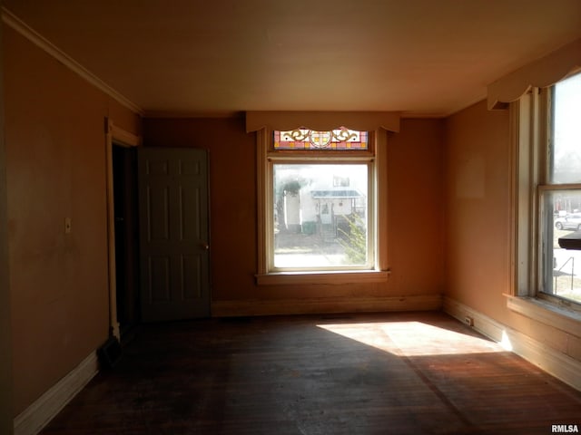 empty room featuring wood finished floors, baseboards, and ornamental molding