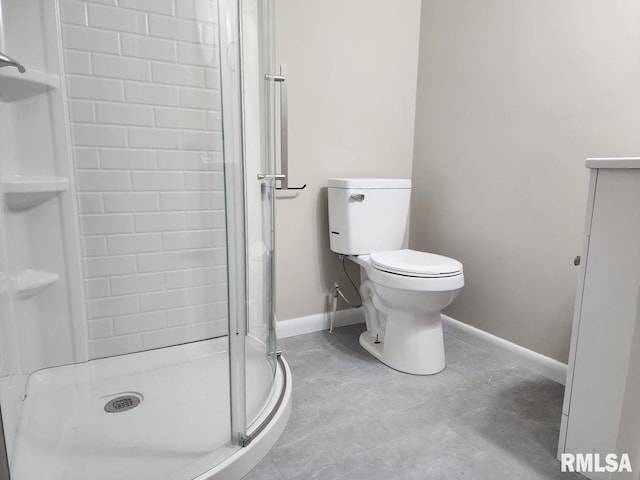 bathroom with a shower stall, toilet, and baseboards