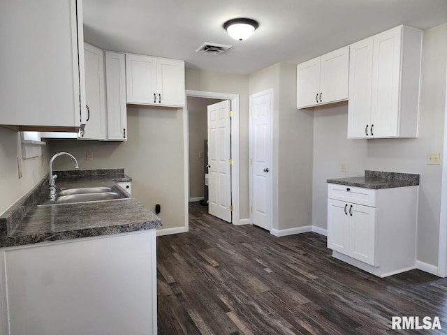 kitchen featuring a sink, visible vents, dark countertops, and white cabinets