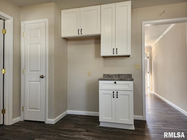 kitchen with dark countertops, crown molding, baseboards, dark wood finished floors, and white cabinets