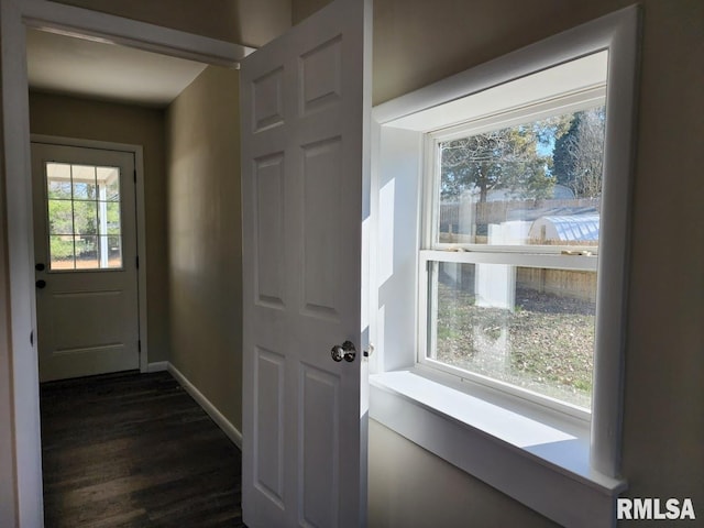 doorway featuring dark wood-type flooring and baseboards