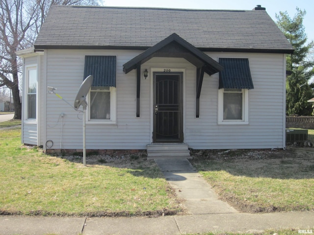 bungalow-style house featuring entry steps, a front lawn, and a shingled roof