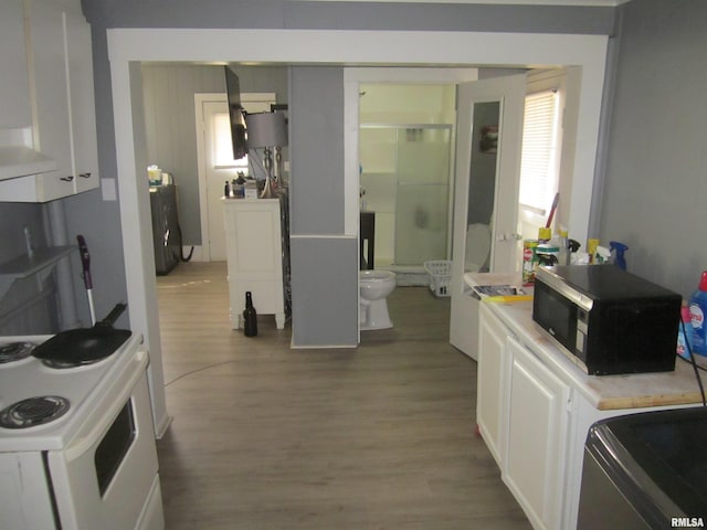 kitchen with light wood finished floors, light countertops, electric stove, exhaust hood, and white cabinets