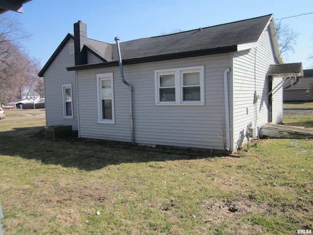 rear view of house with a yard, central AC unit, and a chimney