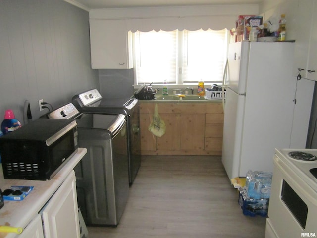 laundry area with laundry area, washing machine and dryer, light wood finished floors, and a sink