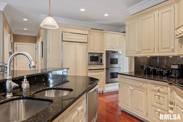 kitchen featuring a sink, cream cabinets, wood finished floors, crown molding, and built in appliances